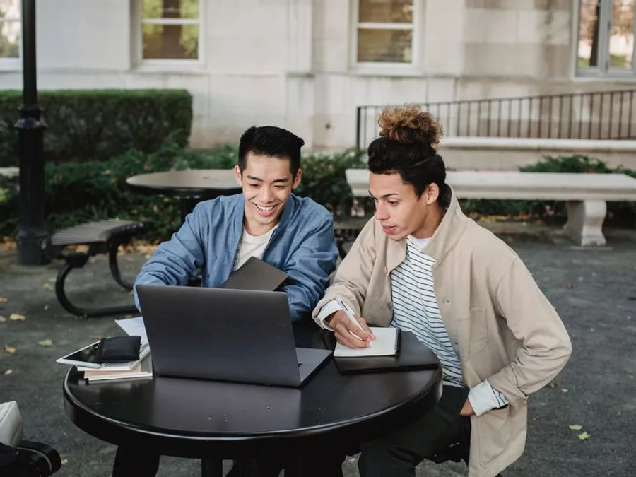 Two students from different backgrounds discussing career pathways around a laptop on campus
